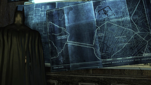 Batman looks towards a city plan found on the wall.